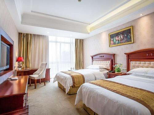 a hotel room with two beds and a desk at Vienna Hotel Suzhou fairyland in Suzhou