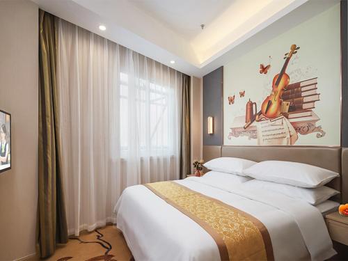 a bedroom with a large bed and a painting on the wall at Vienna Hotel(Nanjin Fuzimiao Muxuyuan Subway Station) in Nanjing