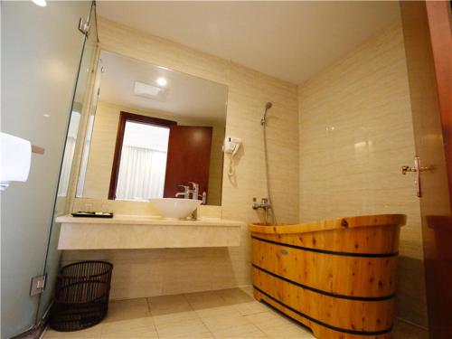 ein Badezimmer mit einer Holzbadewanne und einem Waschbecken in der Unterkunft Vienna Hotel Suzhou Luokou Furniture Store in Suzhou
