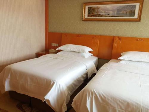 two beds in a hotel room with white sheets at Vienna Hotel Hefei East Changjiang Road in Hefei