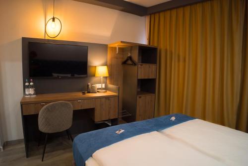 a hotel room with a bed and a desk with a television at Hotel Palatinus in Sopron