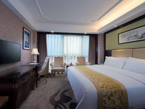 um quarto de hotel com uma cama grande e uma secretária em Vienna 3 Best Hotel Meizhou Mei County People Square em Meizhou