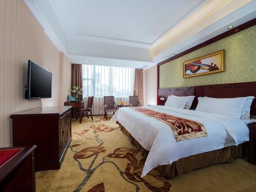 Vienna Hotel Nanning Xianhu في نانينغ: غرفه فندقيه سرير كبير وتلفزيون