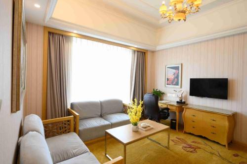 a living room with a couch and a tv at Vienna International Hotel Shanghai Malu Station in Jiading