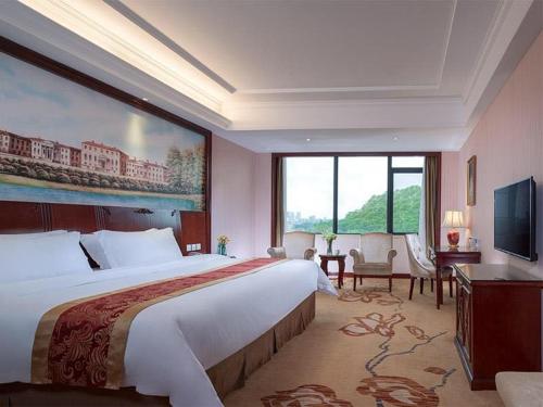 a hotel room with a large bed and a large window at Vienna Hotel Shenzhen Longzhu in Shenzhen