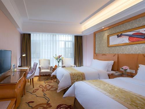 a hotel room with two beds and a television at Vienna Hotel Guangdong Heyuan Lianping in Lianping