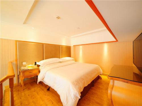 um quarto com uma grande cama branca e uma mesa em Vienna Hotel Shenzhen Nanxin Road em Shenzhen