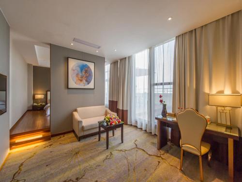a living room with a couch and a desk in a hotel room at Vienna International Hotel Diecai Wanda High Speed ​​Rail Station in Guilin