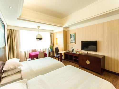 a hotel room with two beds and a flat screen tv at Vienna International Hotel Zhangjiajie Tianmen Mountain in Zhangjiajie