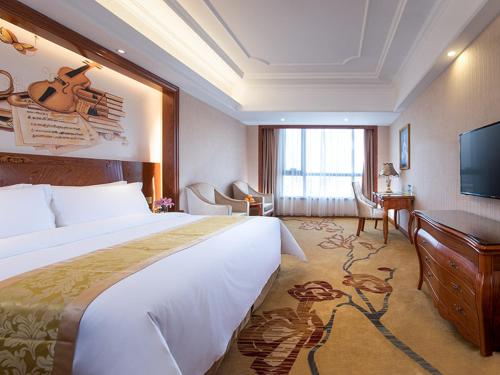 Vienna International Hotel Jieyang Yangmei Yudu في Jieyang: غرفة الفندق بسرير كبير ومكتب