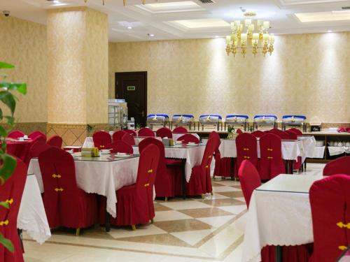 a dining room with tables and red chairs and a chandelier at Vienna Hotel Shanghai Happy Valley in Songjiang