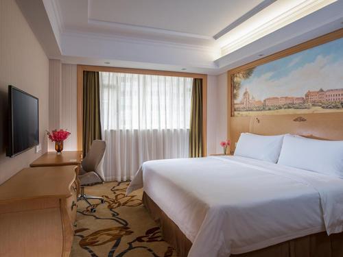 a hotel room with a large bed and a window at Vienna Hotel Shenzhen Nanshan Yilida in Shenzhen