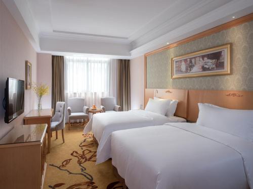 a hotel room with two beds and a table and chairs at Vienna Hotel Shenzhen Buji Ganli Road in Longgang