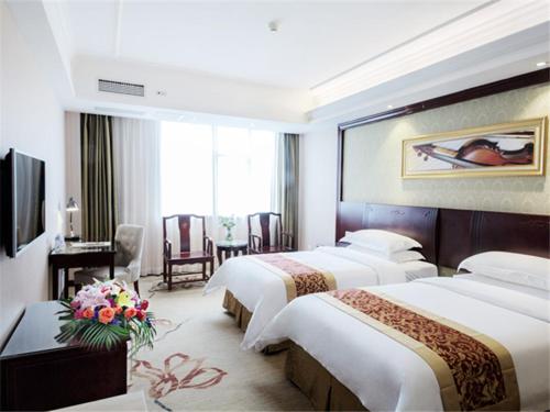a hotel room with three beds and a desk and a room at Vienna Hotel Guilin North Road in Guilin