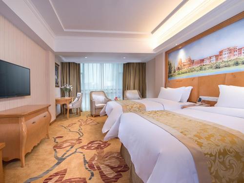 a hotel room with two beds and a flat screen tv at Vienna Hotel Guangdong Zhongshan Tanzhou in Zhongshan