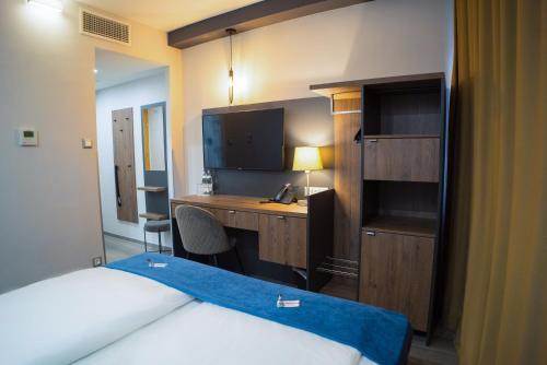 a hotel room with a desk and a bed at Hotel Palatinus in Sopron
