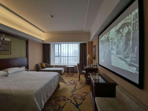 ein Hotelzimmer mit einem Bett und einem Flachbild-TV in der Unterkunft Vienna Hotel Xinyu Fenyi South Changshan Road in Fenyi