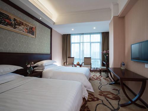 a hotel room with three beds and a flat screen tv at Vienna Hotel Guangzhou Shaheding Metro Station in Guangzhou