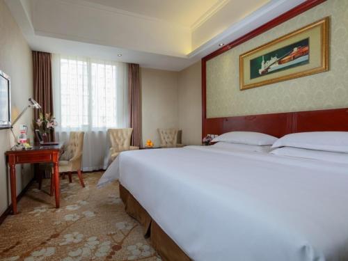 a hotel room with a large bed and a desk at Vienna Hotel Chengdu Exhibition Centre in Chengdu