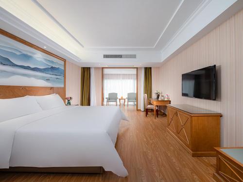a hotel room with a large bed and a flat screen tv at Vienna hotel (huizhou ancient city store, shexian county, huangshan city, anhui province) in She