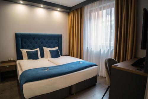a bedroom with a bed with a blue headboard and a window at Hotel Palatinus in Sopron