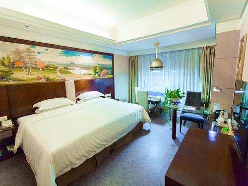 a hotel room with a large bed and a desk at Vienna International Hotel Zhangjiajie Tianmen Mountain in Zhangjiajie