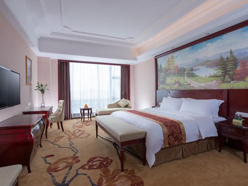 Xinyi的住宿－維也納國際酒店茂名信宜新尚路店，卧室配有一张大床,墙上挂着一幅大画