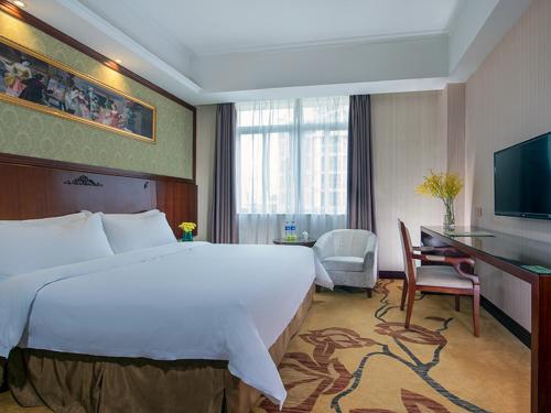 um quarto de hotel com uma cama grande e uma secretária em Vienna Hotel Shiqiao Metro Station em Guangzhou