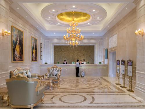 un gran vestíbulo con una lámpara de araña y una persona de pie en él en Vienna International Hotel Dongguan Shilonghuixing Business Central, en Dongguan
