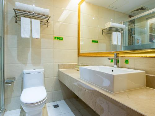 ein Badezimmer mit einem Waschbecken, einem WC und einem Spiegel in der Unterkunft Vienna Hotel Banxuegang Road in Longgang