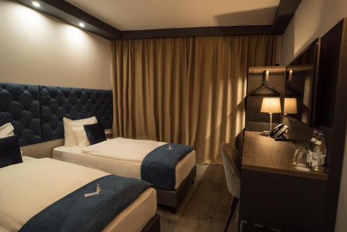 a hotel room with two beds and a desk at Hotel Palatinus in Sopron