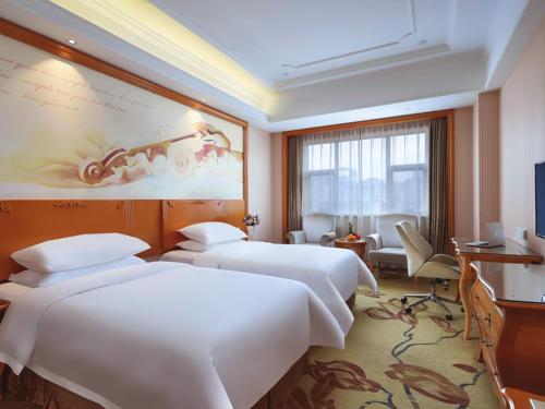 a hotel room with two beds and a television at Vienna International Hotel Nanjing South Railway Station in Nanjing