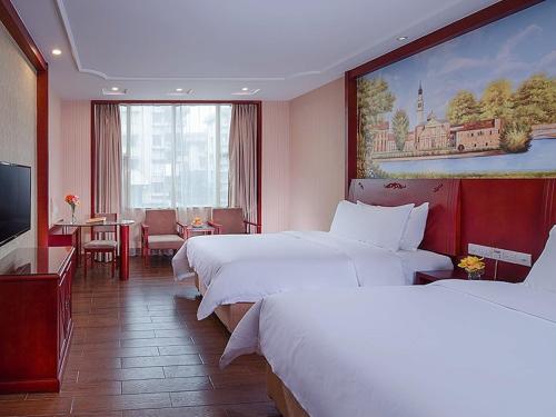 NanhaiにあるVienna International Hotel Guangzhou Jiaokou Subway Stationのベッド3台、テーブル、ダイニングルームが備わる客室です。