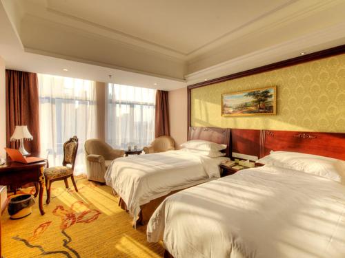 a hotel room with two beds and a desk at Vienna Hotel Shanghai Happy Valley in Songjiang