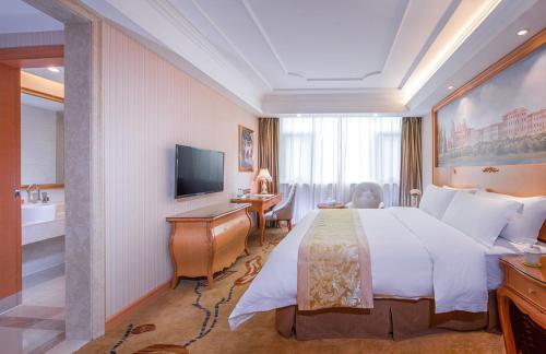 a hotel room with a large bed and a bathroom at Vienna International Hotel Puning International Commodity City in Puning