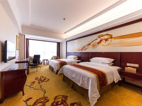 松江区にあるVienna Hotel Songjiang Wanda Guangfulin Roadのベッド2台とデスクが備わるホテルルームです。