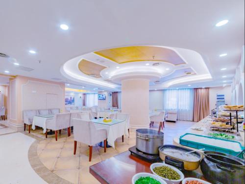 un restaurant avec des tables blanches, des chaises blanches et de la nourriture dans l'établissement Vienna Hotel Guilin Lingchuan Shunxiang No.1 Mansion, à Guilin
