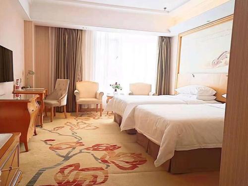 a large hotel room with two beds and a desk at Vienna Hotel Liaocheng University in Liaocheng