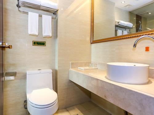 a bathroom with a sink and a toilet and a mirror at Vienna International Hotel Shanghai Fengxian Nanqiao in Fengxian