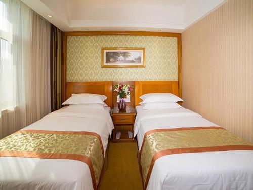 two beds in a hotel room with at Vienna Hotel Shandong Yantao Golden Beach Taishan Road in Yantai