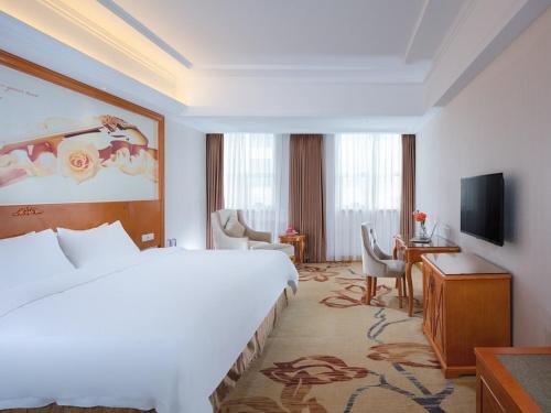 um quarto de hotel com uma cama grande e uma televisão em Vienna Hotel Dongguan Mayong Centre Avenue em Dongguan