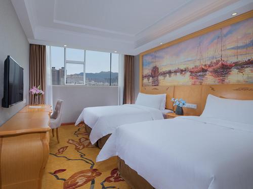 a hotel room with two beds and a flat screen tv at Vienna 3 Best Hotel(Guangdong Yangchun Bus Station Shop ) in Yangjiang