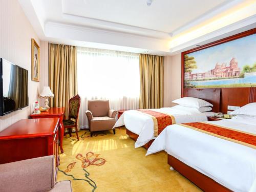 a hotel room with two beds and a television at Vienna International Hotel Shanghai Fengxian Nanqiao in Fengxian