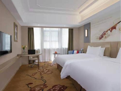 Pokój hotelowy z dużym łóżkiem i telewizorem w obiekcie Vienna International Hotel (Hunan Changde Taoyuan Longba) w mieście Zhangjiang
