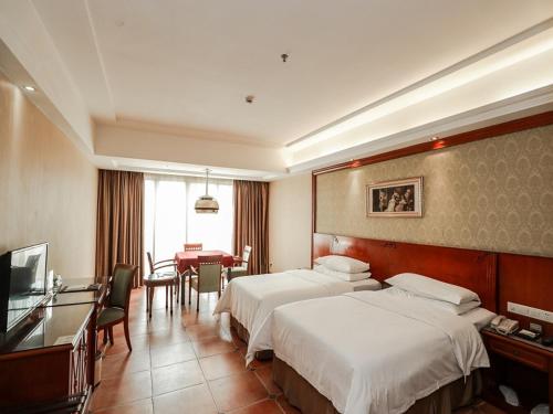 a hotel room with two beds and a desk at Vienna Hotel Dongguan Hou street Wanda Plaza in Dongguan