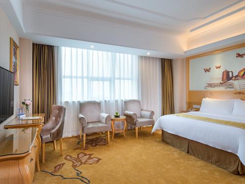 東莞市にあるVienna Hotel Guangdong Gaozhou City East Passenger Depotのベッドと机と椅子があるホテルの部屋
