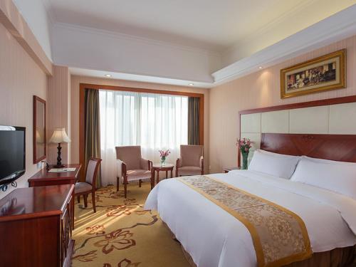 ein Hotelzimmer mit einem großen Bett und einem TV in der Unterkunft Vienna Hotel Foshan Nanhai Avenue Branch in Foshan