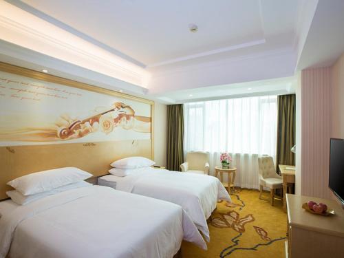 a hotel room with two beds and a television at Vienna Hotel Huizhou Dahuxi in Huizhou