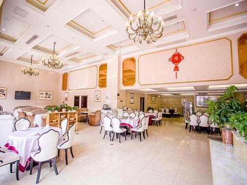 un comedor con mesas y sillas blancas y una lámpara de araña en Vienna Hotel - Jinzhou Branch, en Guangzhou