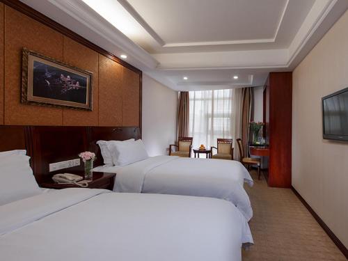 a hotel room with two white beds and a window at Vienna Hotel Shenzhen Pingdi in Longgang